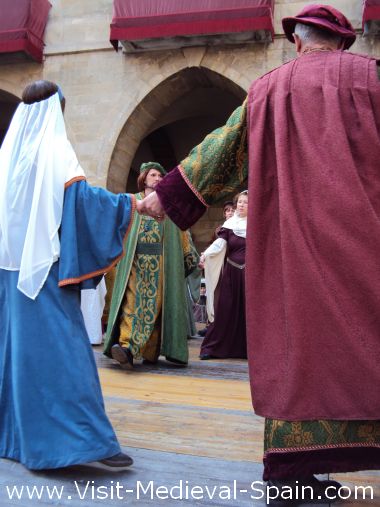 Dancers in traditional medieval costume perform a dance on stage in front of Manresa town hall 