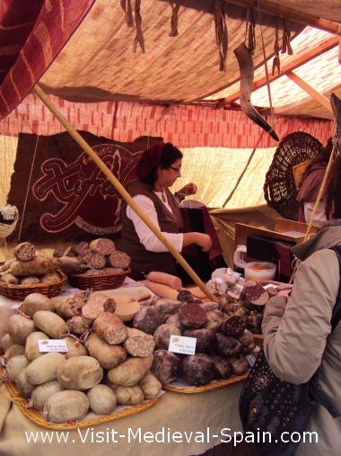 This photograph shows a stallholder in traditional medieval dress hard at work selling traditional food in her medieval market stall.Participants in the Fira de L'Aixada, Catalonia Spain
